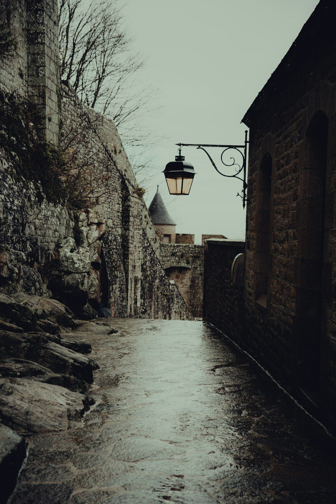 Narrow stone alley with a hanging lantern in the fog